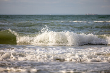Crashing waves lapping on the sandy beach one after another under a blue sunset sky, selective focus used. High quality photo