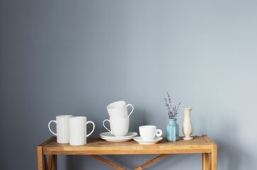 white cups and vases on wooden shelf on gray background