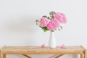 pink   hydrangea in white vase on wooden shelf  on background white wall