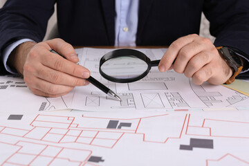 Professional cartographer working with cadastral map at table, closeup