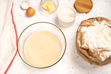 the process of making dough for pancakes with ingredients on a light table, eggs and flour are whipped with a mixer
