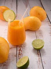 Orange beverage macro with lime slice on white vintage wooden desktop with mango © ALEKSEI