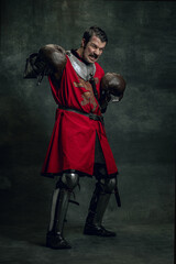 Portrait of medieval warrior or knight with dirty wounded face in boxing gloves isolated over dark...