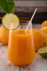 Carrot beverage macro with lime on white vintage wooden desktop with mangos