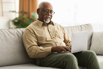Smiling Senior Black Man Using Laptop Computer At Home