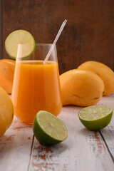 Mandarine juice with lime slice on white vintage wooden desktop with mangos © ALEKSEI