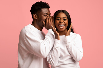 Handsome black guy whispering his girlfriend something exciting