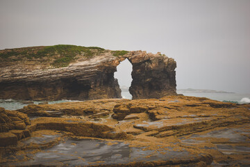 stone arch in the sea with a rock in the foreground