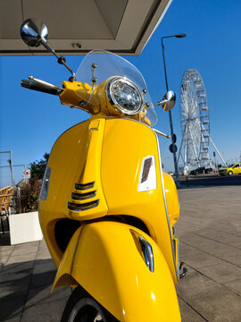 A yellow scouter with the Constanta Ferris Wheel and clear blue sky in the background on a sunny day.