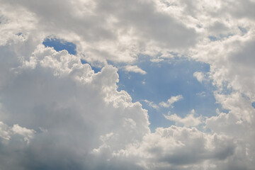 Obraz premium Cloudy sky with clearing of the blue sky in gap between cumulus clouds before the rain in summer.