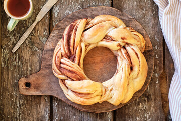 Cinnamon bun wreath. Brioche. Side view, wooden background, coffee, cocoa powder, yeast buns.