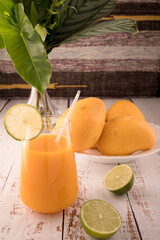 Mango liquor and plate of mango and lime. Vase with tropical leaves on left © ALEKSEI