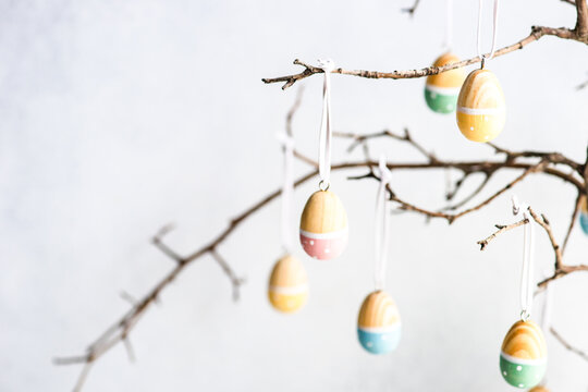 Painted Easter egg decorations hanging on branches in a vase - Powered by Adobe