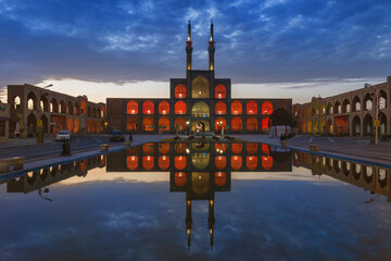 Illuminated façade of the complex of Amir Chaqmaq reflecting in a pond at sunrise, Yzad, Yazd province, Iran