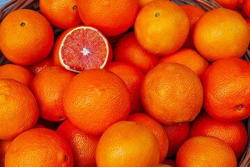 Lots of oranges in a box. Texture of round oranges close up. Sale of fruit at the market and supermarket.