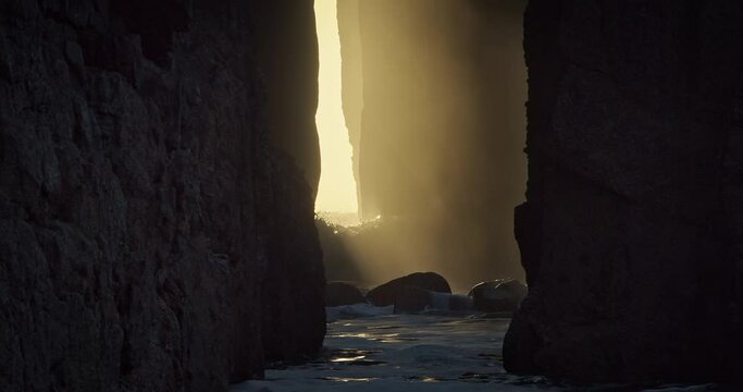 Sun Shining Through Zawn Pyg Rock ArchWith Crashing Waves At Sunset In Nanjizal, Cornwall, United Kingdom. - static