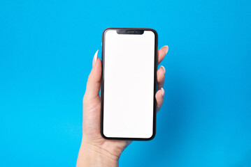 Woman holding mobile phone in hand with empty white screen on blue background