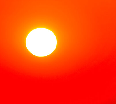 Bright white sun in red sky over hot country.