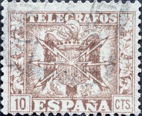 Spain - circa 1940: a postage stamp from Spain, showing a coat of arms with lightning bolts for telegraph and telephone