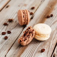 Coffee and vanilla macarons on grey wooden background.