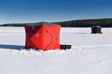 Red and black ice fishing huts in snow on frozen Kempenfelt Bay of Lake Simcoe in winter Barrie...