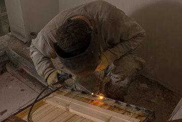 a male welder in a protective mask sits in his hand with an electrode holder. welding concept.