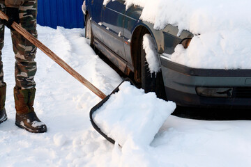 Cleaning the road and the area around the car on the road from snow. The concept of cleaning the...