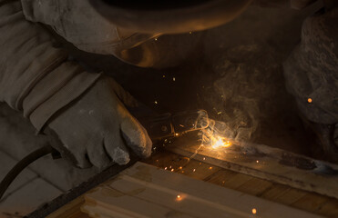 a male welder in a protective mask sits with an electrode holder in his hand. welding seam concept.
