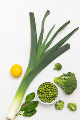 Obraz premium Leek, broccoli and green peas in bowl, lemon.