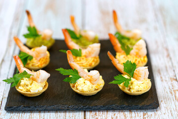 canape with cream cheese and shrimps on black stone plate. close up