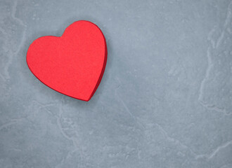 Fototapeta premium Bright Red Heart Cutout on Gray Slate Background Conveying Love, Romance, and Warmth