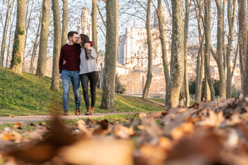 Fototapeta premium Young man and woman couple walking and kissing in a park on valentine's day