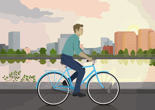 A man is riding along the embankment on a blue bicycle and wearing a blue shirt and trousers. Sports and people. The guy on the bike. A cyclist. To work by bike. Rest and health. 