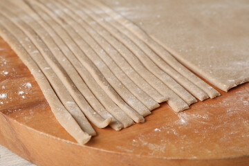 Making homemade soba (buckwheat noodles) on wooden board, closeup