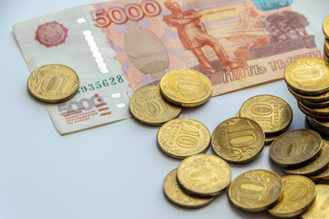 Iron gold coins on the background of a banknote with a face value of 5000 rubles. The concept of finance, investment, savings and cash.