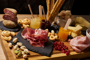 Obraz na płótnie Canvas Wooden cutting board with cold cuts and cheeses