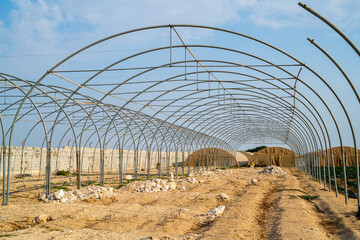 Greenhouse and garden installation. House in the form of an arc. Building objects with transparent roof frames on the ground. Master gardener assembly roof arch installation on the ground. Gardening 