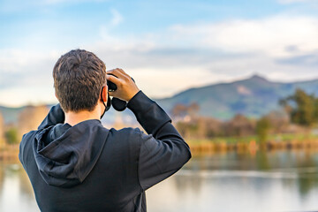 A man looking through binoculars at mountains. Travel concept.