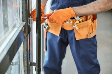 Fototapeta na wymiar Male worker in work gloves repairing door in house