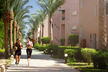 Fototapeta na wymiar woman walking in the city. morning run girl and guy run between palm trees