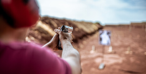 Detail view of shooter holding gun and training tactical shooting, focus on pistol. Shooting range.