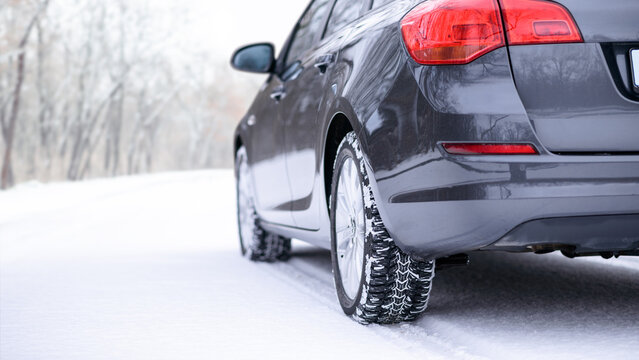 Car on the Winter Road. Close-up Image of Winter Car Tire on the Snowy Road. Safe Driving Concept.