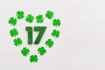 Numeral 17 on white background with frame of paper-cut four-leaf clover leaves, flat lay, copy paste