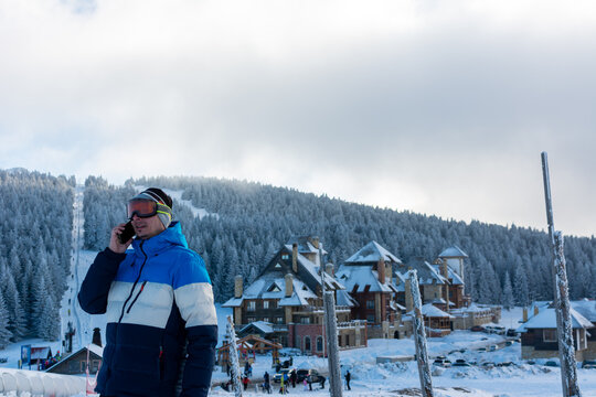 Man talking on the phone at ski resort on a beautiful sunny winter day in the mountains