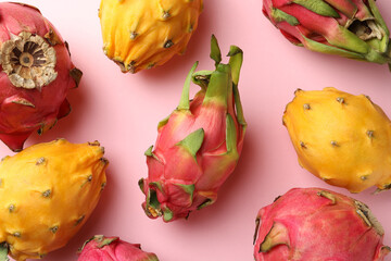 Different pitahaya fruits on light pink background, flat lay