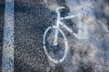 White Bicycle Symbol Painted On The Ground On The Cycle Track Covered With Snow And Ice. - obrazy, fototapety, plakaty