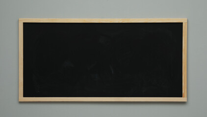 Clean black chalkboard hanging on grey wall