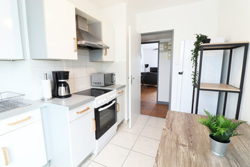 Small kitchen with dining table. Dining table with plants. A coffee maker and a gas stove and fridge. (France - 13.10.2021)