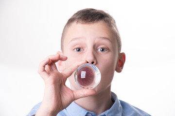 Child speechless with glass ball in front of mouth head-on