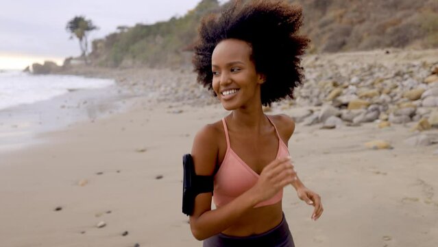 Athletic Somali woman jogging on the beach in Malibu California. Slow motion.